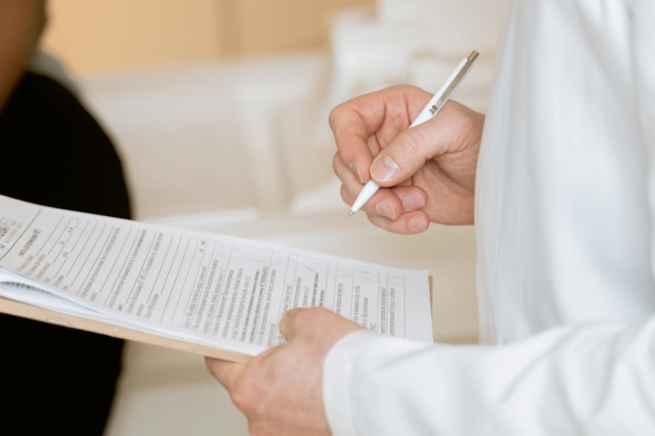 Home A medical professional in a white coat examines a clipboard with patient documents.