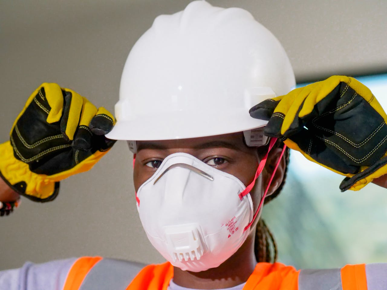 Home Construction worker wearing hardhat, N95 mask, and gloves for safety.
